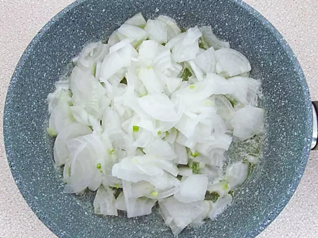 Нарезанный лук в глубокой сковороде со сливочным маслом